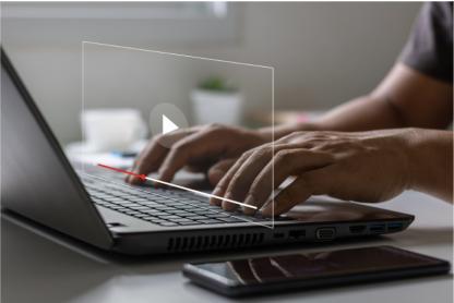 person typing on laptop with video screen and play button
